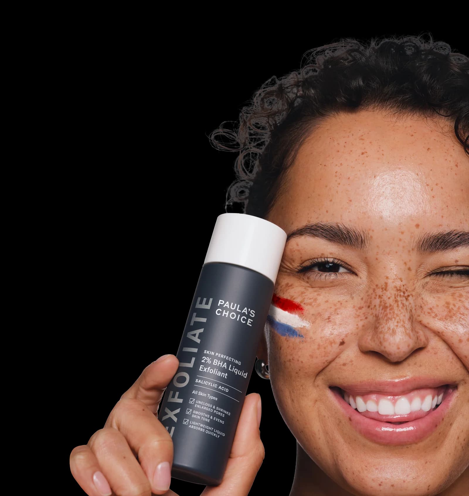The PCFC campaign portrait: a smiling woman with face paint holding Paula’s Choice skincare
